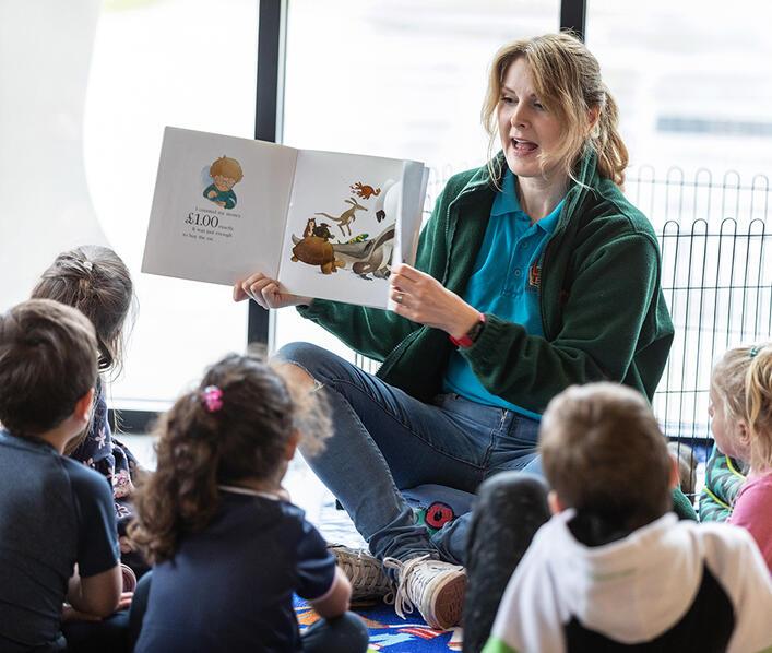 A lady reading a book to children 