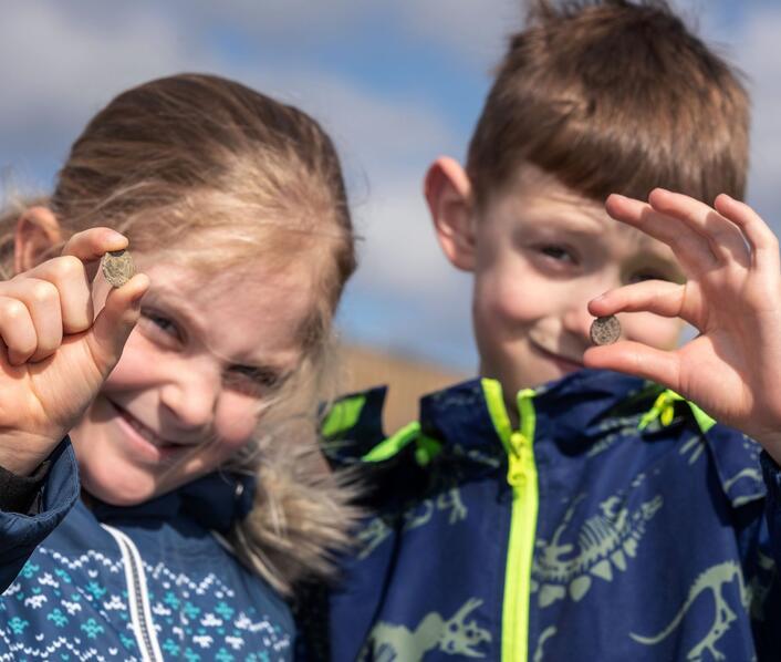 Two children with archaeology finds on a sunny day at Alconbury Weald