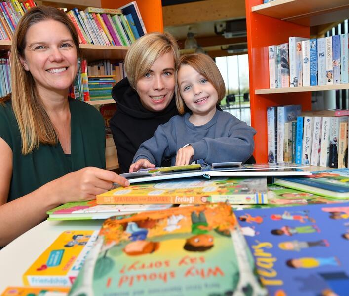 Natalie from Alconbury Weald Library reading some of the new books with Sophia and mum Victoria